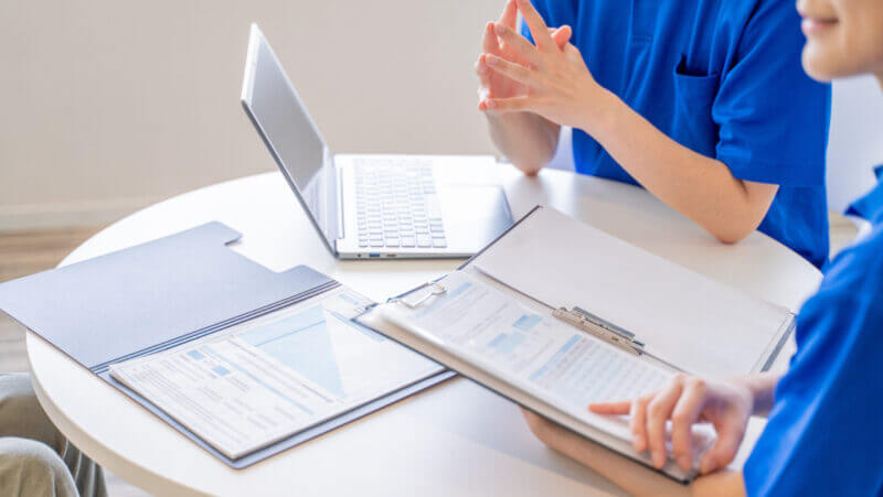 打合せをする男女の介護士の手元